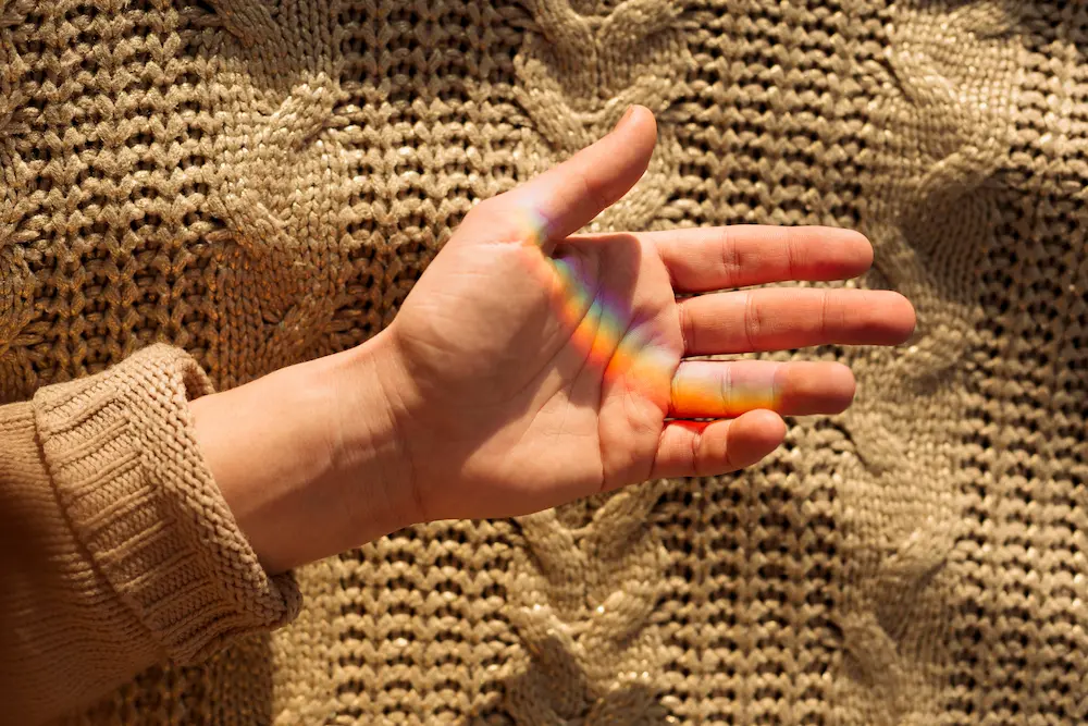 Mão masculina com um sueter e um arco-íris representando a terapia afirmativa LGBTQIAPN+